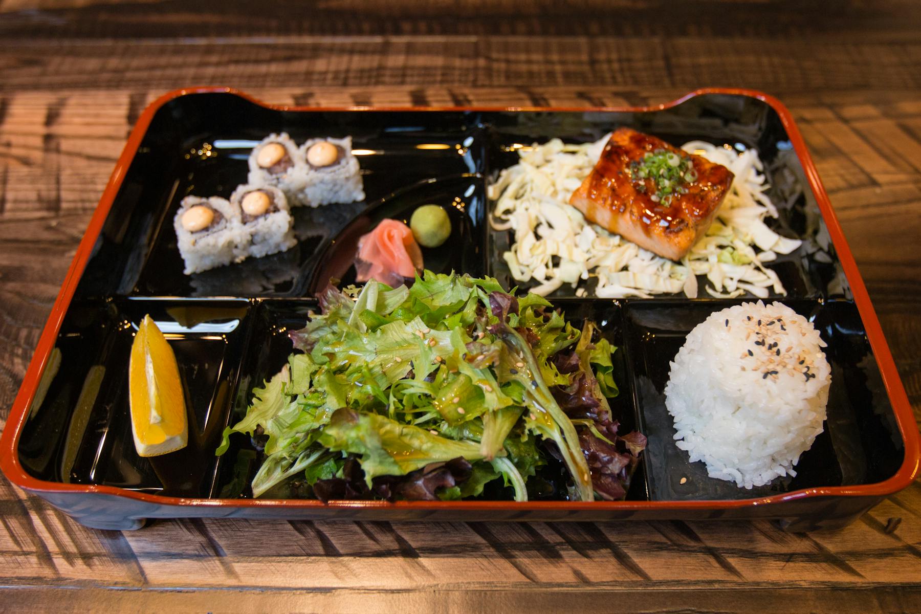 bentobox with different Japanese food, sushi rolls, white rice, coleslaw